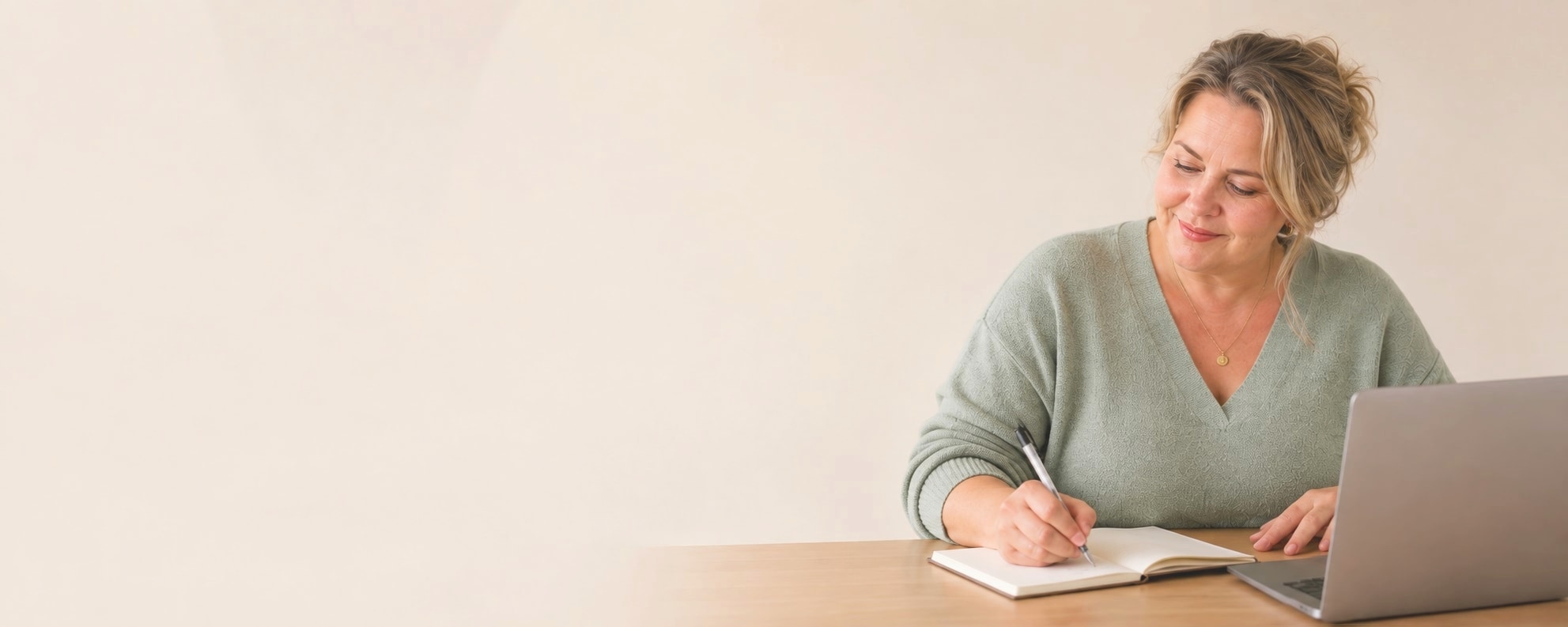 Vrouw maakt aantekeningen in een notitieboek naast haar laptop tegen een rustige beige achtergrond